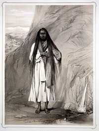 A Hindu man (sadhu) with long hair, cloak and walking stick stands by a rock from which water springs. Lithograph by L.C. Dickinson, 1844, after Emily Eden.