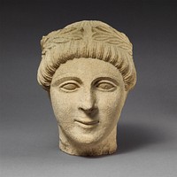 Limestone head of a beardless male votary with a wreath of leaves