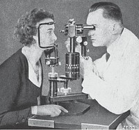 Eye examination with a Zeiss biomicroscopic apparatus. Black and white image of a young woman having her eyes examined by a doctor. Caption Zeiss in the bottom right corner. Biomicroscopy of the eye, vol. 1, p. 35. . Original public domain image from Flickr