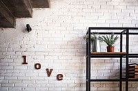 A cozy living room wall features a plant on a minimalist shelf and the word LOVE on the wall, free public domain CC0 image.