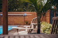 Wooden slatted chairs sit beside the pool on a rainy day, free public domain CC0 image.