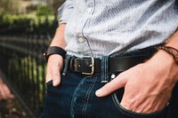 Close up of a man with his hands in his pockets leaning against an iron fence