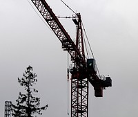 Tower crane backlit against cloudy sky