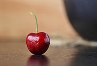 Closeup on red cherry on table. Free public domain CC0 photo.