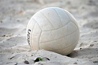 Closeup on white volleyball in sand. Free public domain CC0 photo.