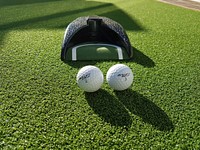 Golf balls and cap on grass field. Free public domain CC0 photo.