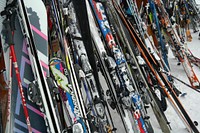 Many ski equipment leaning against wall. Free public domain CC0 image.