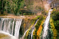 Bridge above flowing waterfall. Free public domain CC0 image.