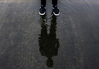 Free person standing on wet ground with black sneakers image, public domain shoes CC0 photo.