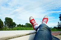 Free person laying crossed leg with red sneakers image, public domain shoes CC0 photo.