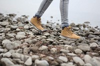 Free person walking on small rocks with brown boots photo, public domain shoes CC0 image.