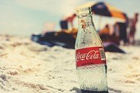 Empty coke glass bottle in sand on beach, location unknown, 15 February 2017. View public domain image source here
