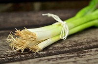 Free spring onion roots bundle, scallions on wooden table photo, public domain vegetable CC0 image.