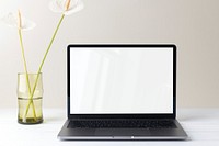 Laptop with blank screen, flower in vase