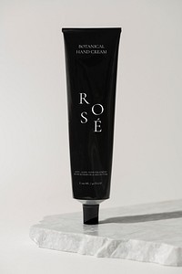 Black hand cream tube, simple skincare product packaging, aluminium collapsible tube, on marble product stand