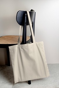 Beige tote bag hanging on a chair, eco-friendly apparel product with blank design