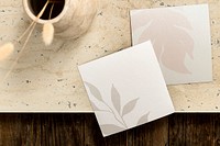 Brown table background with two square business cards flat lay