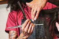 Hair stylist trimming hair of the customer at a barbershop, small business