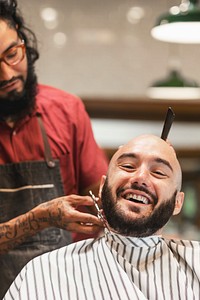 Barber trimming a customer's beard at a barber shop, small business