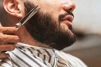 Customer getting a beard trim in a barber shop, small business