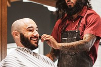 Customer getting a beard trim in a barber shop, small business