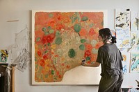 Woman artist painting abstract art on a big canvas, remixed from public domain artwork by Odilon Redon.
