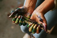 Hands holding paint brush, covered in paint