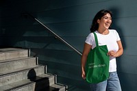 Latina woman with a green tote bag, standing by the staircase