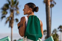 Woman carrying drawstring bag at the beach, green accessory