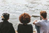 Three diverse friends sitting by the river bank 