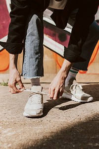 Man tying shoelaces, closeup shot, graffiti wall