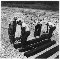  laborers carrying and laying railroad ties for a spur line into a coal storage space for the federal government. Sourced from the Library of Congress.