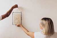 Women hanging frame mockup on white wall psd