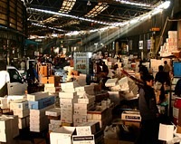 An indoor Japanese market is piles upon piles of styrofoam crates and boxes, the hustle and bustle of selling fresh goods.