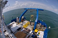 A large clamshell is being lowered off the aft deck of the Bold, to collect a sediment grab sample at the bottom. US EPA photo by Eric Vance. Original public domain image from Flickr