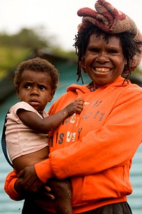 An indigenous Papuan woman and her child are standing in front of puskesmas Seorang Ibu di Papua dengan anaknya di depan Puskesmas di Wamena.