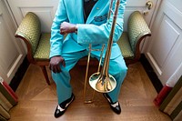 Trombone musician looking at his watch while waiting for his stage performance. Original public domain image from Flickr