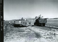 Threshing cicer milkvetch direct from windrows and collecting trash for rethreshing at Bridger PMC, Sep 1968. 17-ft long elevator is mounted on combine and operated by gas power. Rethreshing increases seed recovery about one-third. Original public domain image from Flickr