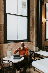Senior man working on digital tablet at coffee shop