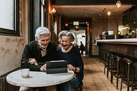 Grandparents in video call on digital tablet at cafe