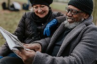 Couple reading newspaper on park bench