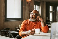 African senior man drinking coffee at bar 