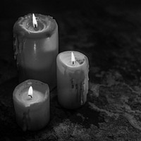 Closeup of lighted candles in the dark grayscale