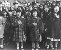 San Francisco, Calif., April 1942 - Children of the Weill public school, from the so-called international settlement, shown in a flag pledge ceremony. Some of them are evacuees of Japanese ancestry who will be housed in War relocation authority centers for the duration. Sourced from the Library of Congress.