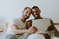 Gay couple using a tablet in bed