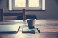 Notebook and a cup of coffee on a wooden table