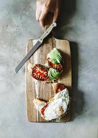 Croissant with tomatoes and avocado on a chopping board