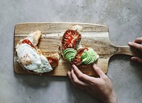 Croissant with tomatoes and avocado on a chopping board