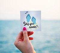 Woman holding note with summer graphic at the beach