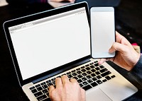 Closeup of hands holding mobile phone with computer laptop background